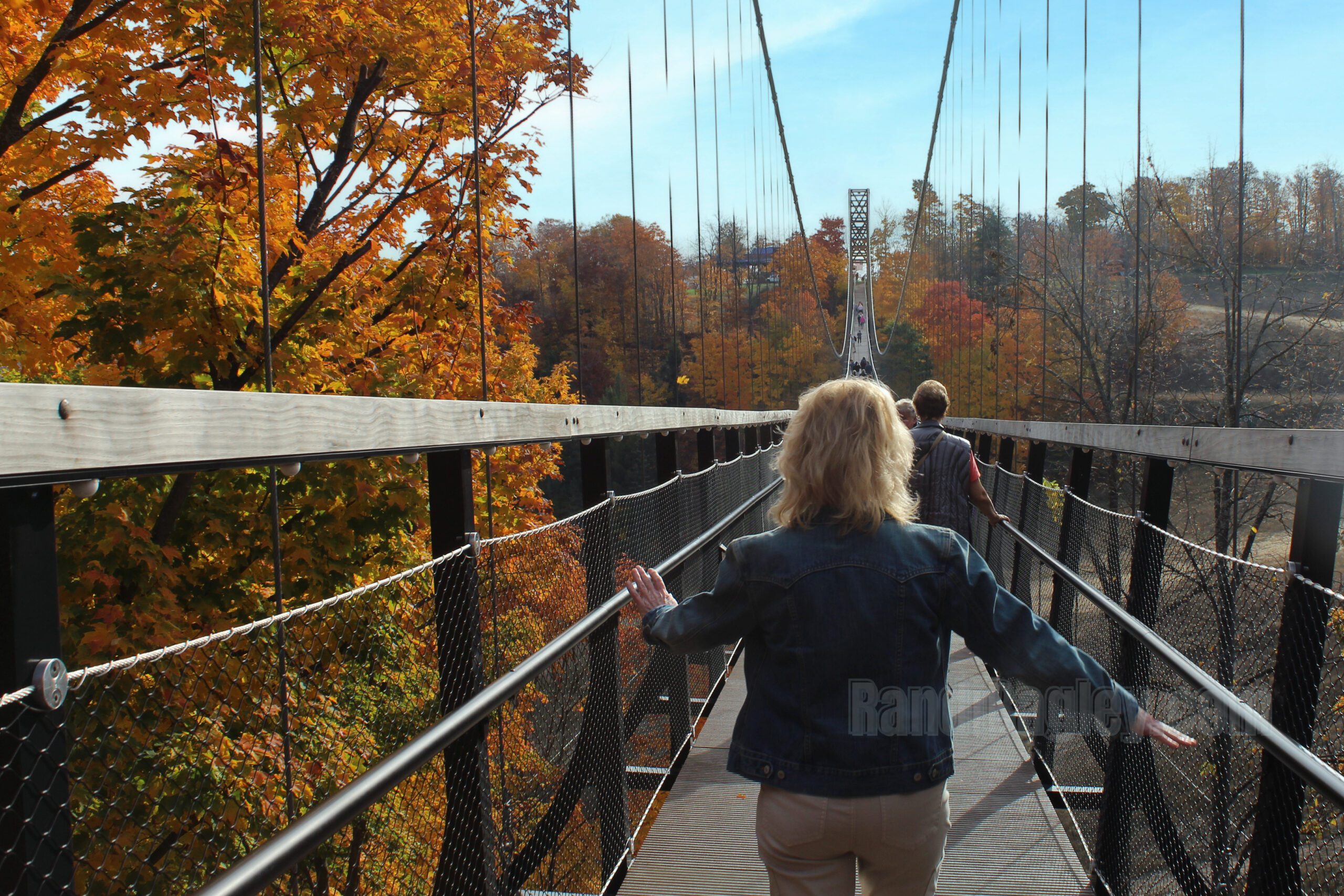 Visitors walking on SkyBridge Michigan with vibrant fall foliage surrounding the bridge.