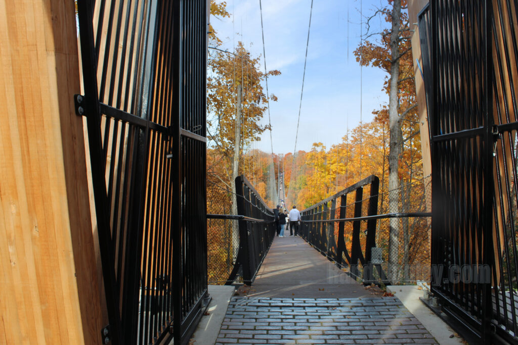 SkyBridge Michigan entrance gate with people walking across the bridge surrounded by autumn colors.